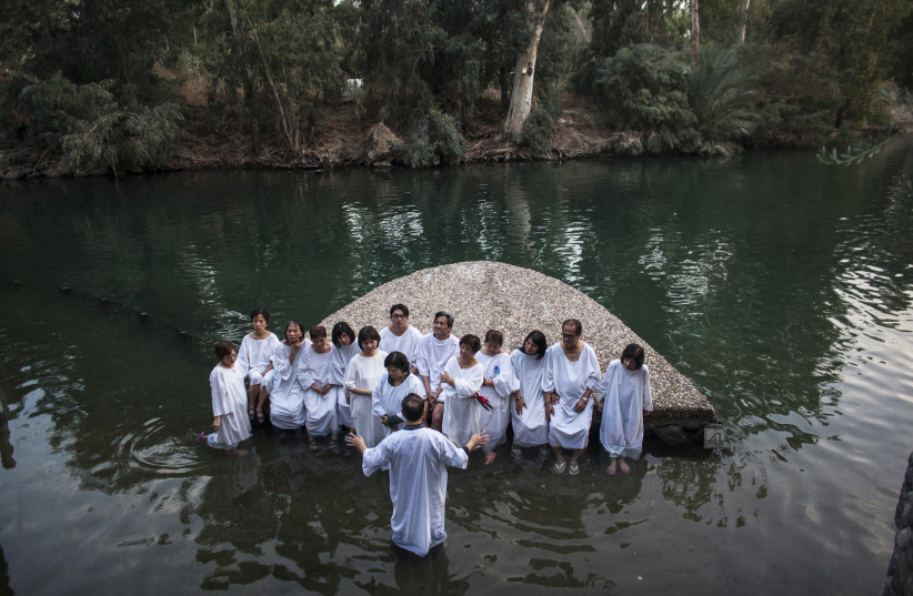  A group of pilgrims gather before being baptized in the Jordan River during a ceremony at the Yardenit baptismal site where it is believed Jesus was baptized. (credit: NIR ELIAS/REUTERS)