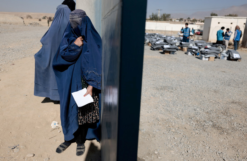  FILE PHOTO: A displaced Afghan woman waits to receive aid supply from UNCHR agency outside a distribution center on the outskirts of Kabul, Afghanistan October 28, 2021. (photo credit: ZOHRA BENSEMRA/REUTERS)