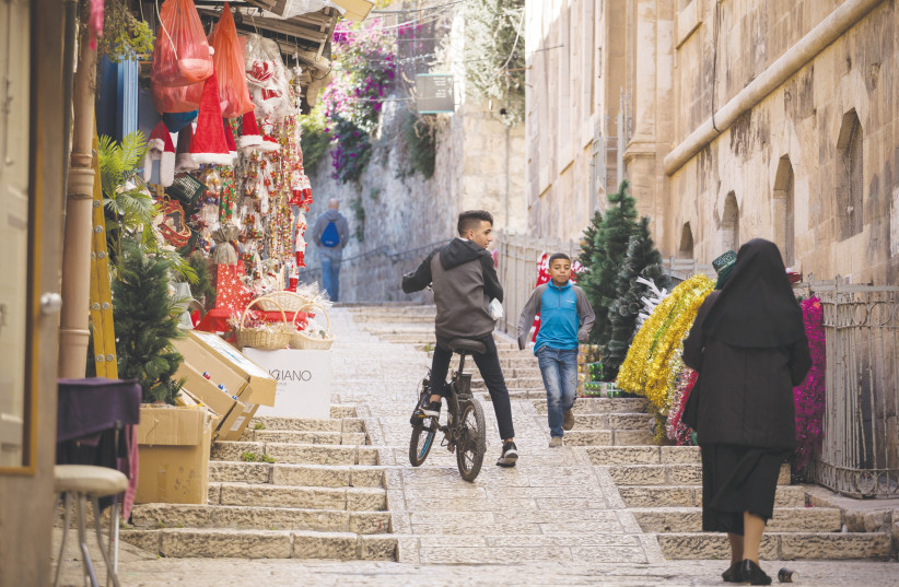  PEOPLE PASS BY a store selling Christmas decorations in the Christian Quarter of Jerusalem’s Old City, in 2019. (credit: HADAS PARUSH/FLASH90)