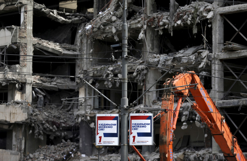  Serbian Progressive Party (SNS) campaign poster is seen in front of a building of the former federal military headquarters destroyed in NATO's bombing campaign in 1999, ahead of Sunday's election in Belgrade (photo credit: REUTERS)