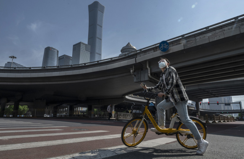  A man stops on a shared bicycle at a main intersection during a quiet morning rush hour in the Central Business District, after the government recommended people work from home to prevent the spread of COVID-19, on May 5, 2022 in Beijing, China. (photo credit: KEVIN FRAYER/GETTY IMAGES/TNS)
