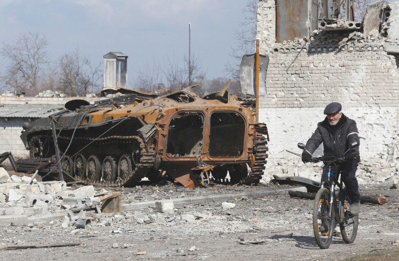  A LOCAL resident rides a bicycle past a charred armored vehicle in the separatist-controlled town of Volnovakha in the Donetsk region, in March. (photo credit: Alexander Ermochenko/Reuters)