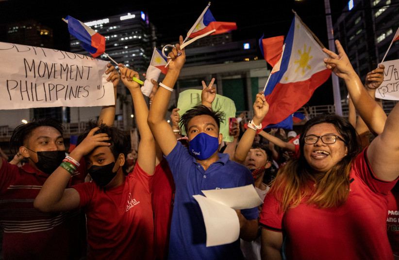 Supporters of presidential candidate Ferdinand ''Bongbong'' Marcos Jr. celebrate as partial results of the 2022 national elections show him with a wide lead over rivals, outside the candidate's headquarters in Mandaluyong City, Philippines, May 9, 2022. (credit: REUTERS/ELOISA LOPEZ)
