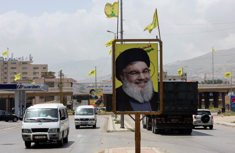 Vehicles drive past pictures of Hezbollah leader Sayyed Hassan Nasrallah, ahead of the parliamentary election that is scheduled for May 15, in Taalabaya, Lebanon. Picture taken May 4, 2022. (photo credit: REUTERS/AZIZ TAHER)