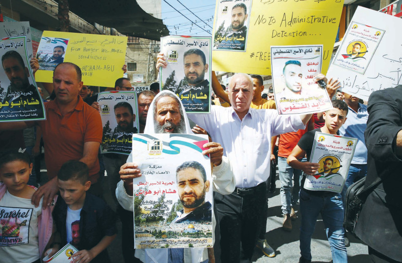  PALESTINIAN DEMONSTRATORS in Dura village on the West Bank hold the pictures of prisoners held by Israel in administrative detention and who had launched a hunger strike, in September. (photo credit: WISAM HASHLAMOUN/FLASH90)