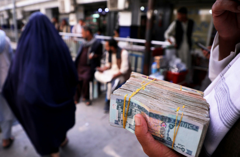  A person holds a bundle of Afghan afghani banknotes at a money exchange market, following banks and markets reopening after the Taliban took over in Kabul, Afghanistan, September 4, 2021. (credit: REUTERS/STRINGER)