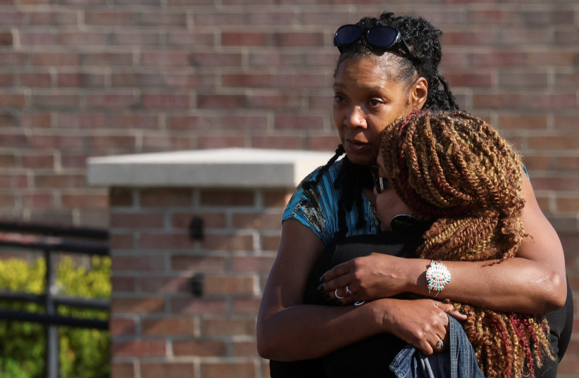  Mourners embrace each other, while attending a vigil for victims of the shooting at a TOPS supermarket in Buffalo, New York, US. (credit: REUTERS/BRENDAN MCDERMID)