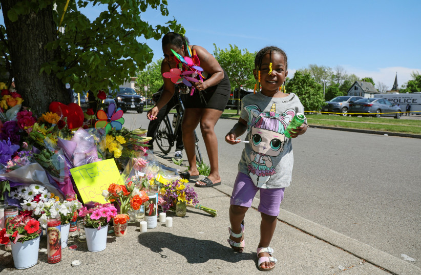  A woman leaves tributes at a memorial for victims near the scene of a shooting at a TOPS supermarket in Buffalo, New York, US May 15, 2022. (credit: REUTERS/BRENDAN MCDERMID)