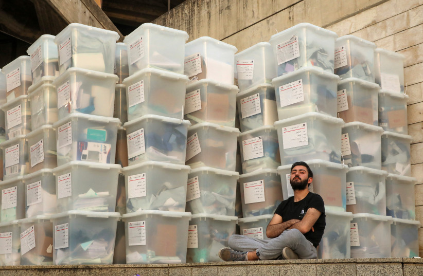 An electoral worker sits next to boxes as Lebanese await the official election results for the rest of the districts in Lebanon's parliamentary election, at the Justice Palace in Jdeideh, Lebanon, May 16, 2022. (credit: REUTERS/MOHAMED AZAKIR)
