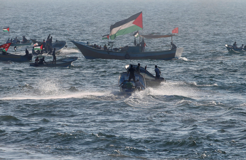  Palestinians sail with boats towards the maritime border with Israel as smoke rises from a burning tire during a protest calling for lifting the Israeli blockade on Gaza, in the Mediterranean Sea off the coast of the northern Gaza Strip September 10, 2018 (photo credit: MOHAMMED SALEM/REUTERS)