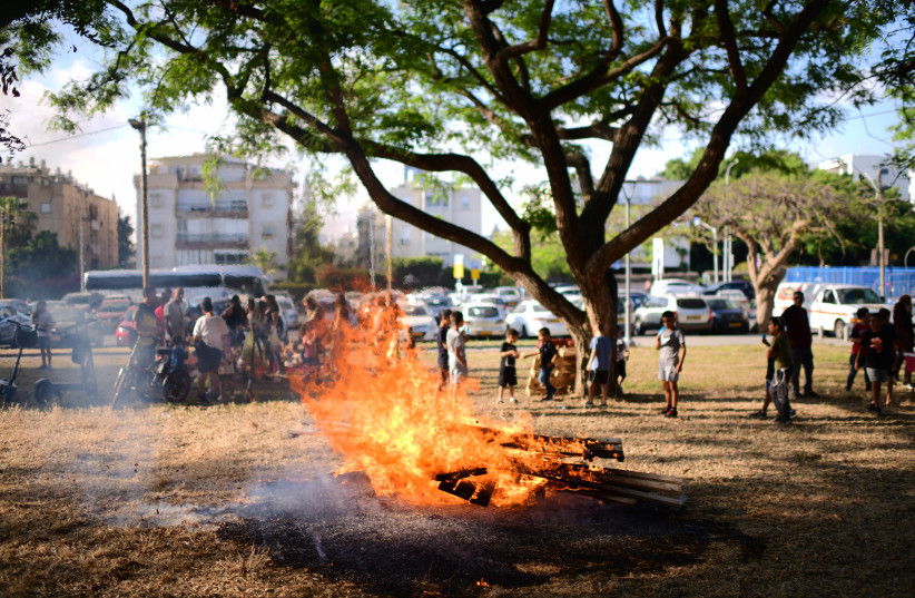  Children and their parents gather around a bonfire to celebrate the Jewish holiday of Lag Baomer, on May 17, 2022, in Tel Aviv. (credit: TOMER NEUBERG/FLASH90)