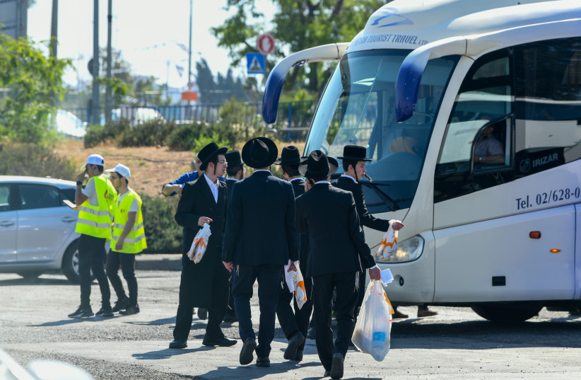  Jewish worshipers board the bus to the Lag B'omer festival in Meron, in Jerusalem, on May 18, 2022. (credit: Arie Leib Abrams/Flash90)