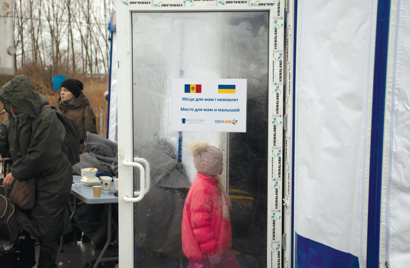  A Ukrainian girl walks past an IsraAID sign in Moldova.  (credit: ETHAN SCHWARTZ)