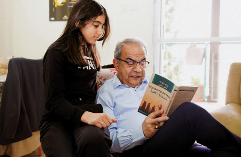  Magally reading the book to his granddaughter, Ghena, at his home in Nazareth (credit: Mona Abu Shhady)