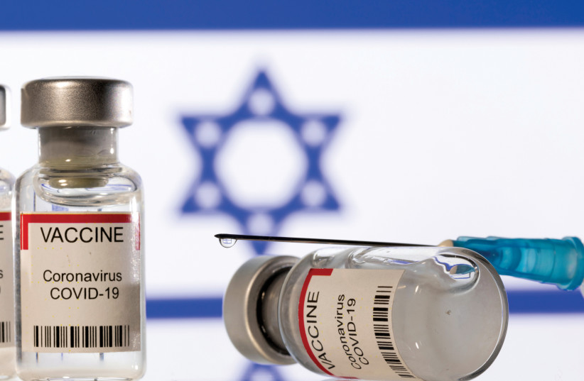  Vials containing the corona vaccine and a syringe are displayed in front of an Israeli flag. (credit: DADO RUVIC/REUTERS)