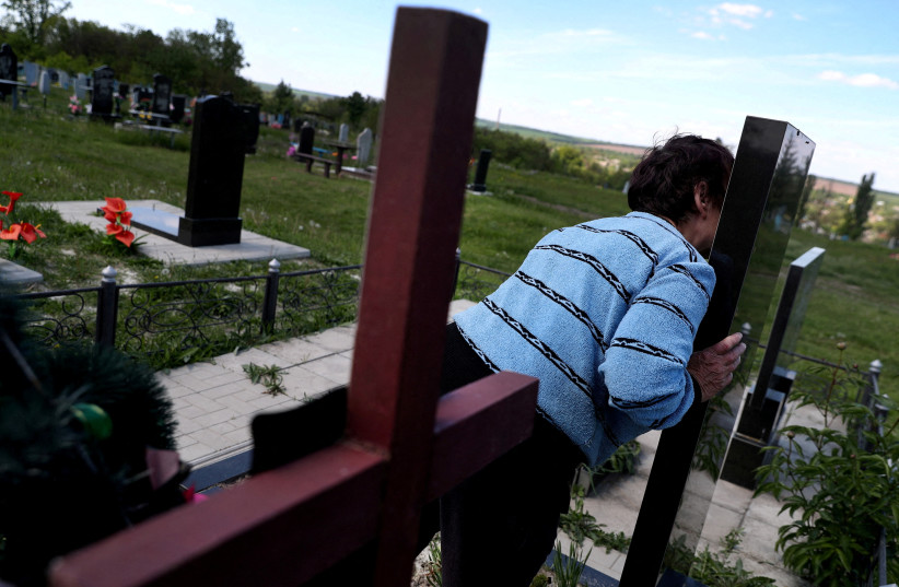  Kateryna Shelikhova, widow of 62-year-old Oleksandr Shelipov, who was shot dead by a Russian soldier sentenced to life in prison for killing an unarmed civilian in the first war crimes trial since Russia's invasion, kisses the grave of her daughter while visiting her husband's grave. (credit: REUTERS)