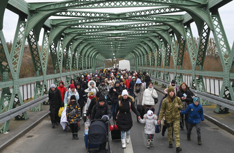  UKRAINIAN REFUGEES cross a bridge at the buffer zone to the border with Poland, Zosin-Ustyluh crossing, western Ukraine, in March (photo credit: DANIEL LEAL/AFP via Getty Images)