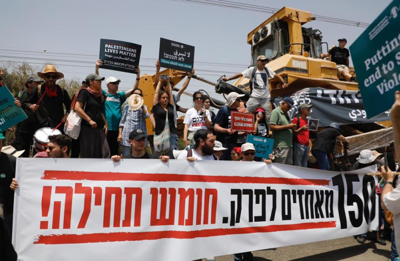  Left-wing protestors call on the government to dismantle 150 settlements, with a bulldozer allegedly intended for the razing of Homesh in the background, on May 28, 2022. (photo credit: PEACE NOW)