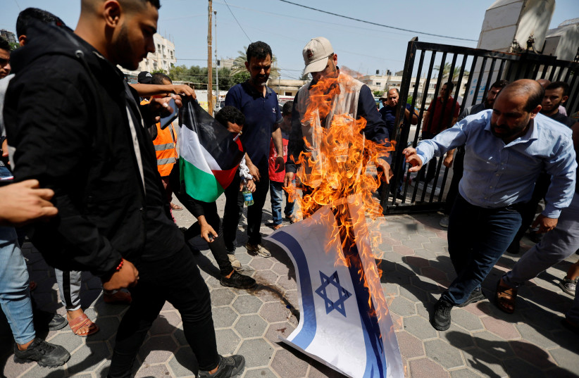  Palestinians burn a representation of an Israeli flag during a protest over tensions in Jerusalem's al-Aqsa Mosque, in Khan Younis, in the southern Gaza Strip, on Jerusalem Day, on May 29, 2022.  (credit: IBRAHEEM ABU MUSTAFA/REUTERS)
