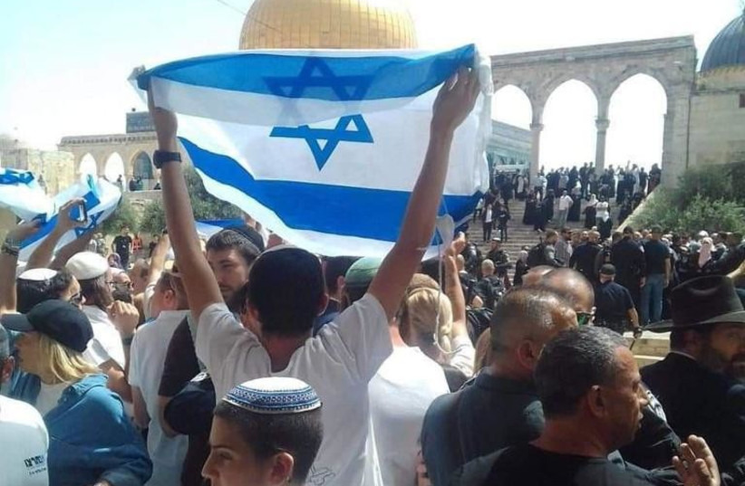  An Israeli flag is seen being raised on the Temple Mount on Jerusalem Day, on May 29, 2022. (credit: HOZRIM LAHAR NGO)