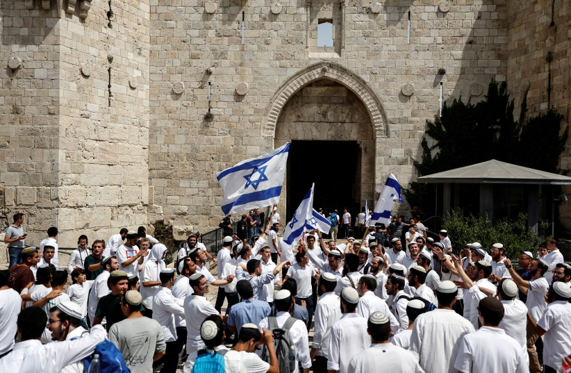  Israelis wave flags and dance by Damascus gate to Jerusalem's Old City, on Jerusalem Day, May 29, 2022. (credit: AMMAR AWAD/REUTERS)