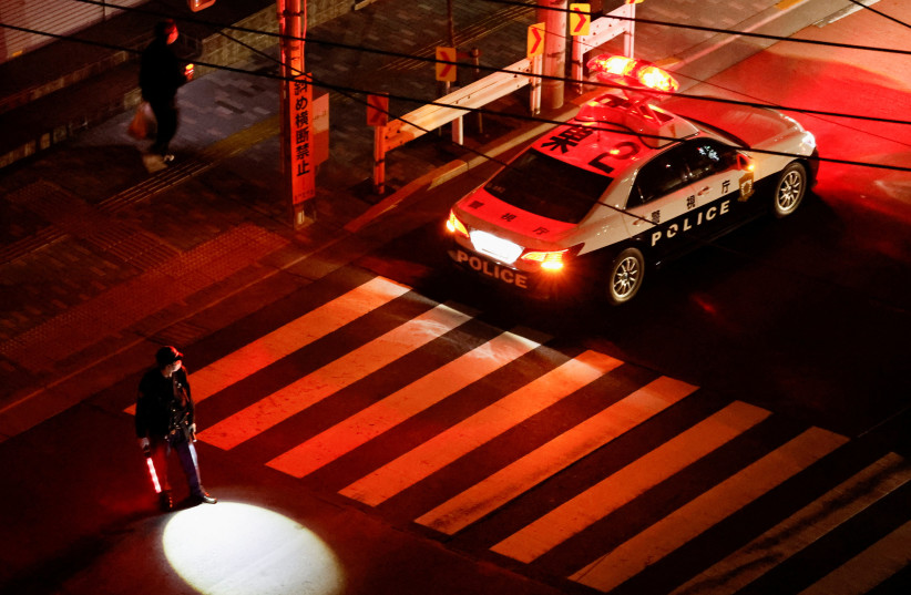  A police officer tries to control traffic on the street during an electric stoppage after an earthquake in Tokyo (photo credit: REUTERS)