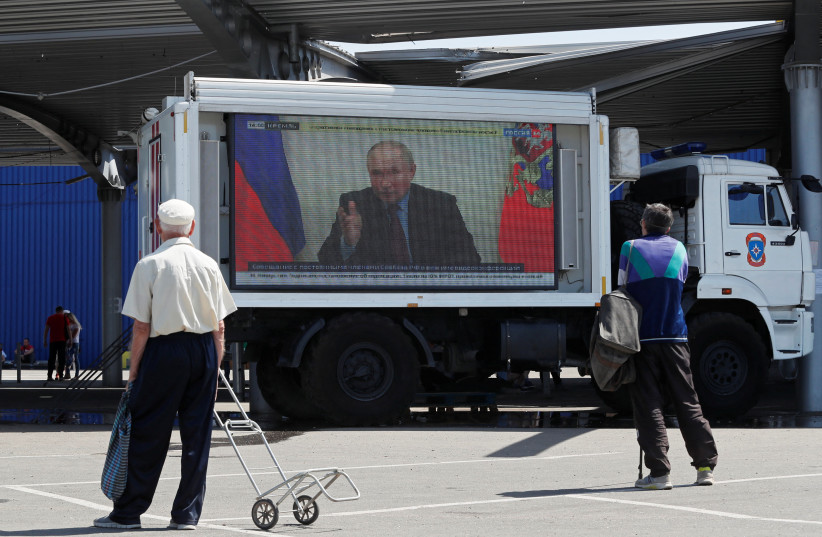  Russian President Vladimir Putin is seen on a screen broadcasting Russian TV news programs at a humanitarian aid distribution point during Ukraine-Russia conflict in the southern port city of Mariupol, Ukraine May 30, 2022.  (photo credit: REUTERS/ALEXANDER ERMOCHENKO)