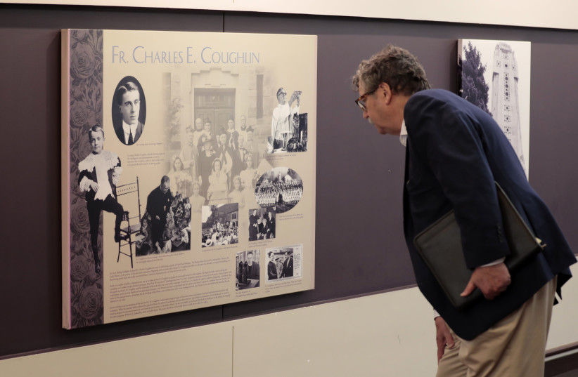  Levi Smith, a Jewish attendee at the event discussing ''The Jewish-Catholic Relationship'' at the National Shrine of the Little Flower in Royal Oak, Mich, inspects a plaque discussing the history of its antisemitic founder, Father Charles Coughlin, May 31, 2022.  (credit: JEFF KOWALSKY/JTA)