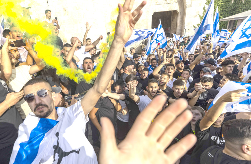  Young Jewish men hold Israeli flags as they dance at Damascus Gate in Jerusalem’s Old City on Jerusalem Day on Sunday. (photo credit: OLIVIER FITOUSSI/FLASH90)