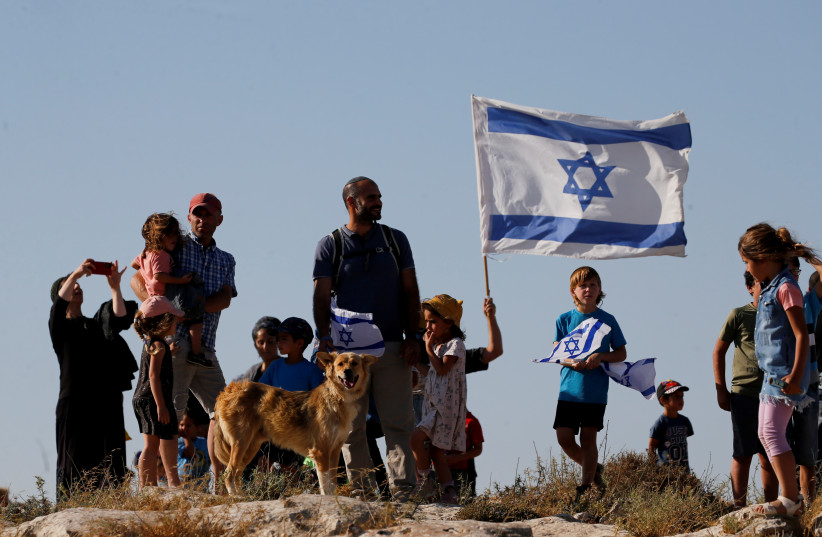  Jewish settlers look on during a march near Hebron in the West Bank, June 21, 2021 (photo credit: REUTERS/MUSSA QAWASMA)