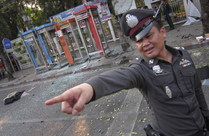 A policeman gestures at the site where a man was injured when a bomb he was carrying exploded, in central Bangkok February 14, 2012 (credit: DAMIR SAGOLJ/ REUTERS)