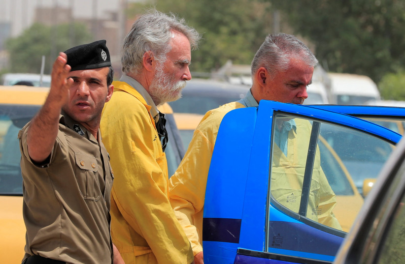  Iraqi policemen escort Jim Fitton from Britain and Volker Waldmann from Germany in handcuffs, who are suspected of smuggling ancient artefacts out of Iraq, outside a court in Baghdad, Iraq, May 22, 2022. (credit: REUTERS/THAIER AL-SUDANI)