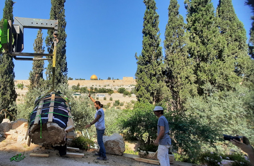   A member of the Italian restoration team works with Haifa forklift driver Mokles Hatib to release the first capital after it was lifted over a wall in the hermitage garden of the Church of Gethsemane. (photo credit: JUDITH SUDILOVSKY)