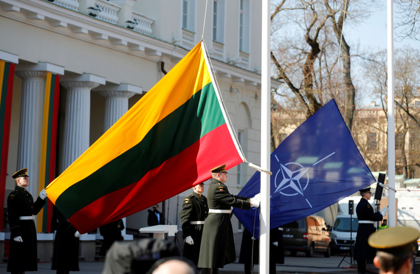  Lithuanian Army soldiers hold Lithuanian and NATO flags during the celebration of the 15th anniversary of Lithuania's membership in NATO in Vilnius, Lithuania March 30, 2019. (photo credit: Ints Kalnins/Reuters)