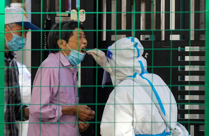  A resident gets tested for the coronavirus disease (COVID-19) behind barriers of a sealed area, amid new lockdown measures in parts of the city to curb the coronavirus disease (COVID-19) outbreak in Shanghai, China June 9, 2022. (credit: ALY SONG/REUTERS)