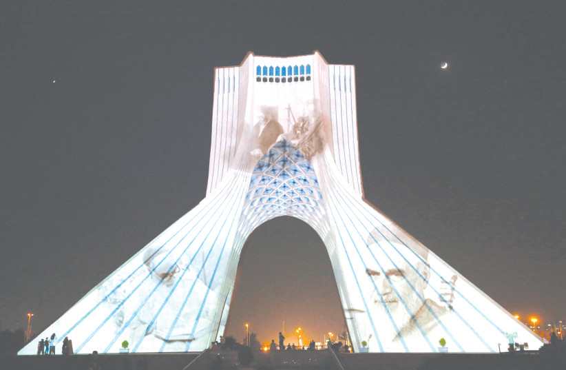  IRAN’S AZADI (Freedom) tower is illuminated with pictures of the late supreme leader Ayatollah Ruhollah Khomeini, to mark the 33rd anniversary of his death, in Tehran earlier this month. (photo credit: AFP VIA GETTY IMAGES)