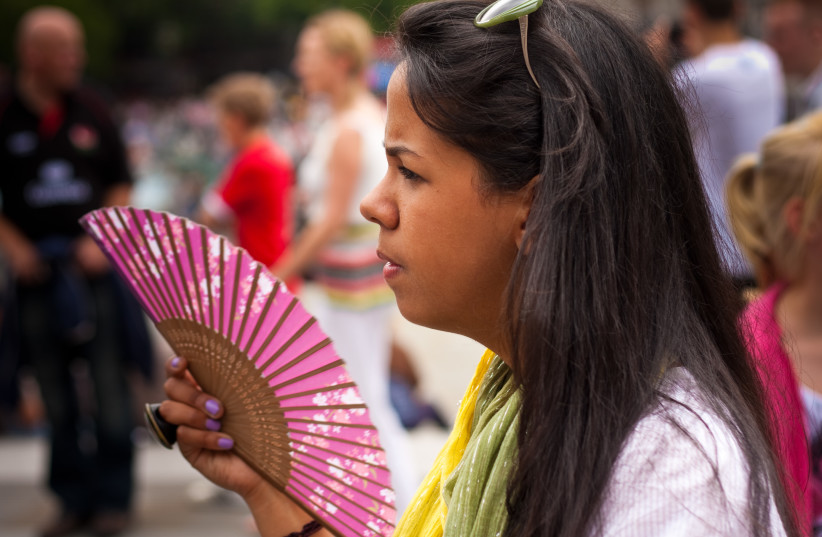  A woman fans herself in the summer heat (Illustrative) (photo credit: FLICKR)