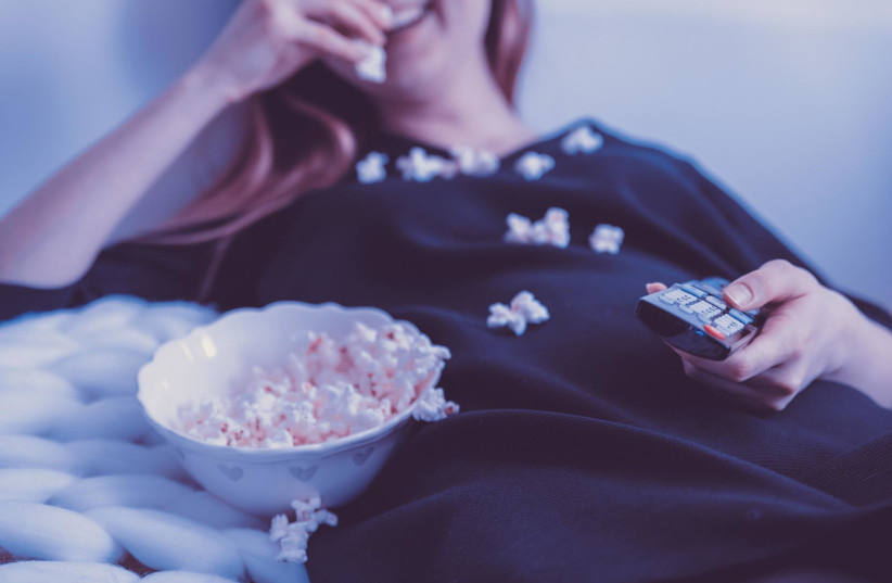  A person sitting in front of a television, snacking; illustrative. (photo credit: JAN VASEK/PIXABAY)