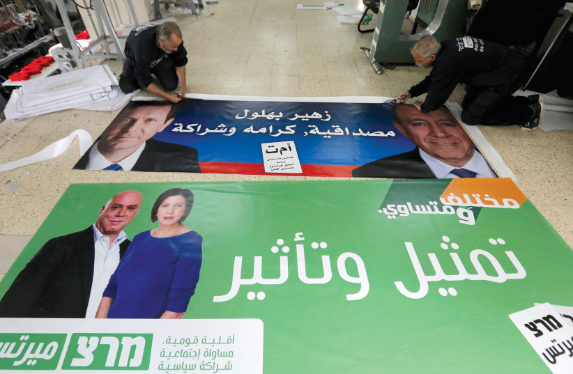  Workers cut freshly printed election campaign posters in Arabic that feature Isaac Herzog (top left), who headed the Zionist Union party, and Zehava Galon (bottom left), at a print shop in Baqa al-Gharbiya on March 2, 2015.  (credit: AMMAR AWAD/REUTERS)