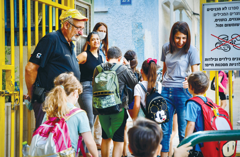  YOUNG STUDENTS are welcomed to school on the first day of classes after the holidays, last September.  (photo credit: AVSHALOM SASSONI/FLASH90)