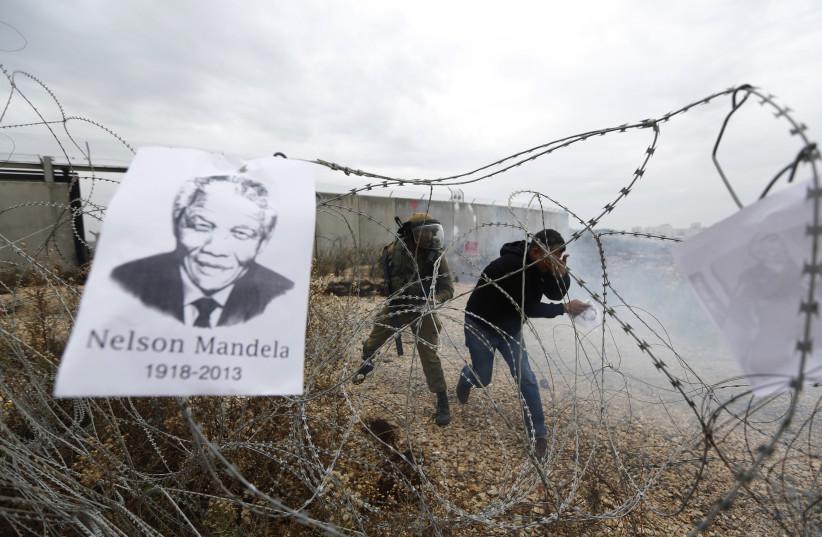  A placard depicting former South African President Nelson Mandela hangs on a barbed wire during clashes with Palestinians and Israeli security forces, near Ramallah December 6, 2013.  (photo credit: REUTERS/MOHAMAD TOROKMAN)