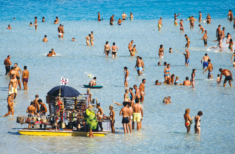  PEOPLE SUNBATHE on the beach in the Italian town of Stintino, at the tip of Sardinia, Italy. The island is one of the Blue Zones, where a large segment of the population lives beyond 100. (credit: Alessandro Bianchi/Reuters)