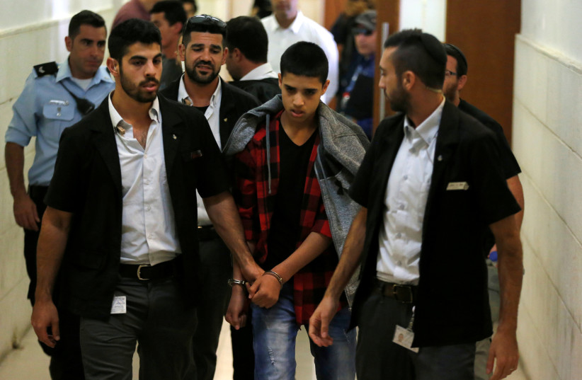 Ahmed Manasra, a 14-year old Palestinian, who was convicted of attempted murder for his role in an attack of a 13-year-old Israeli boy in 2015, leaves the courtroom after his sentencing at the district court in Jerusalem (photo credit: REUTERS/AMMAR AWAD)
