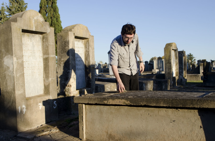 Javier Sinay visits the Jewish cemetery in Moise Ville, Argentina, during a visit to the village in 2013.  (credit: Paula Salischiker/JTA)