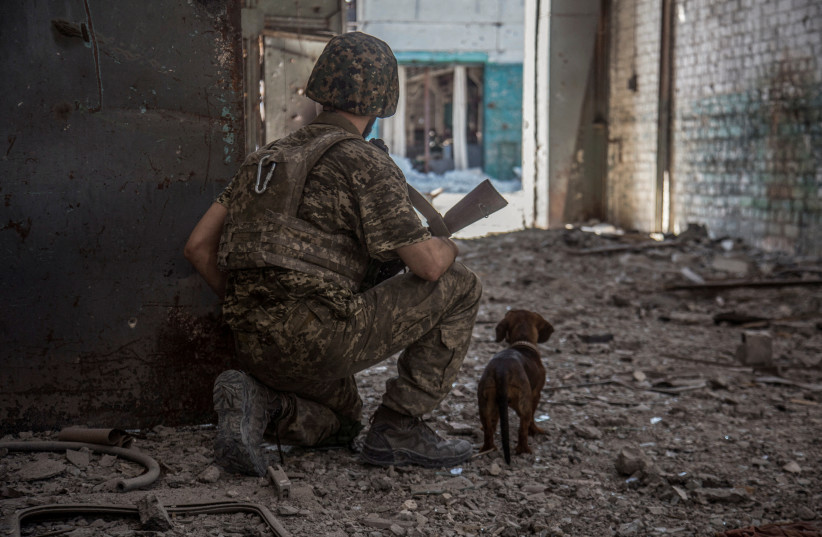  A Ukrainian service member with a dog observes in the industrial area of the city of Sievierodonetsk, as Russia's attack on Ukraine continues, Ukraine June 20, 2022.  (credit: Oleksandr Ratushniak/Reuters)