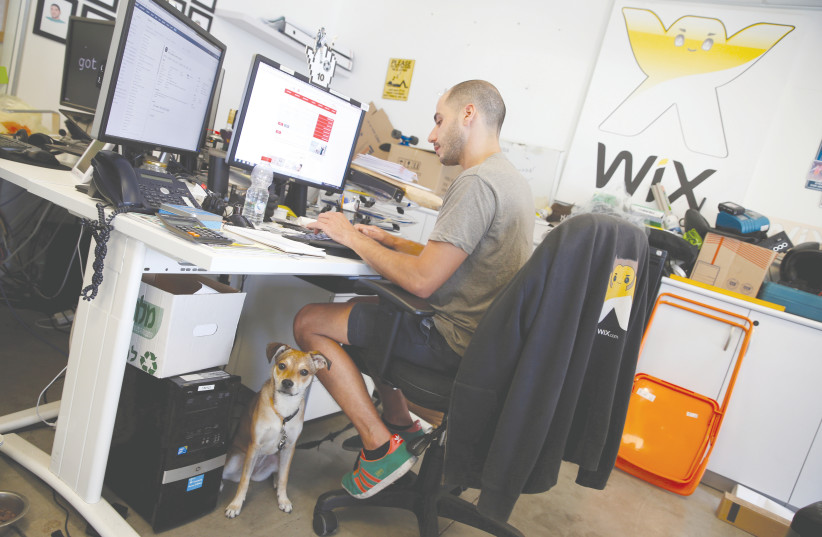  AN EMPLOYEE works at website-designer firm Wix.com offices in Tel Aviv in 2016.  (photo credit: BAZ RATNER/REUTERS)