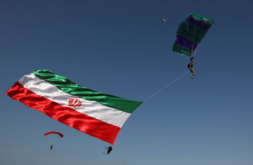 An Iranian Army paratrooper flies with the Iranian flag during a military exercise dubbed 'Zulfiqar 1400', in the coastal area of the Gulf of Oman, Iran, November 7, 2021. (credit: IRANIAN ARMY/WANA (WEST ASIA NEWS AGENCY)/HANDOUT VIA REUTERS)