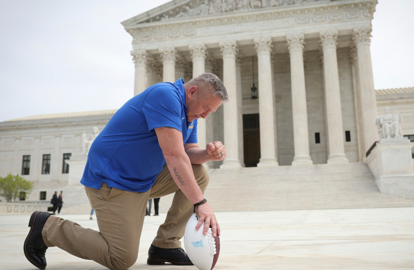  Former Bremerton High School assistant football coach Joe Kennedy takes a knee in front of the US Supreme Court after his legal case, Kennedy vs. Bremerton School District, was argued before the court, April 25, 2022. (photo credit: WIN MCNAMEE/GETTY IMAGES/JTA)