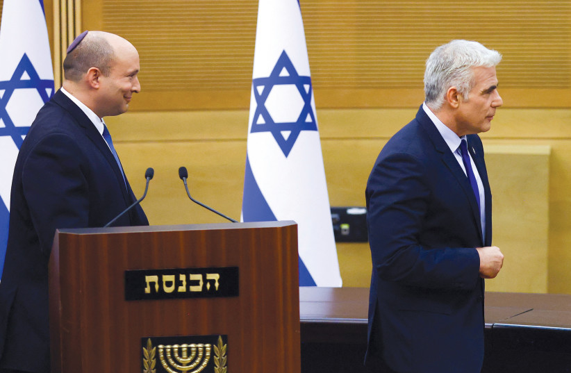  Outgoing Prime Minister Naftali Bennett and incoming interim Prime Minister Yair Lapid are seen walking away in the Knesset plenum in Jerusalem. (credit: RONEN ZVULUN/REUTERS)