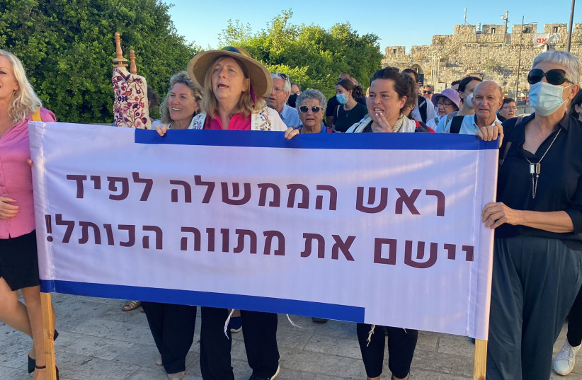 Women of the Wall hold up a sign reading "Prime Minister Lapid, implement the Western Wall outline!" (photo credit: WOMEN OF THE WALL)